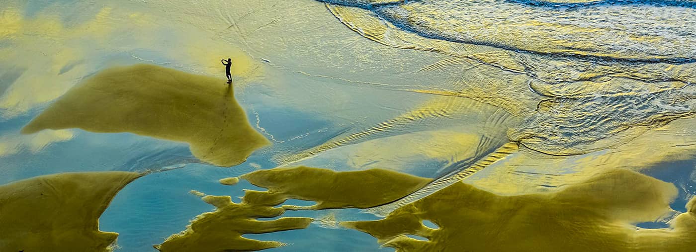 fotógrafo en la playa el sol de mañana teñía las llanuras marea isla nanao dorada y no pudo evitar sostener su teléfono