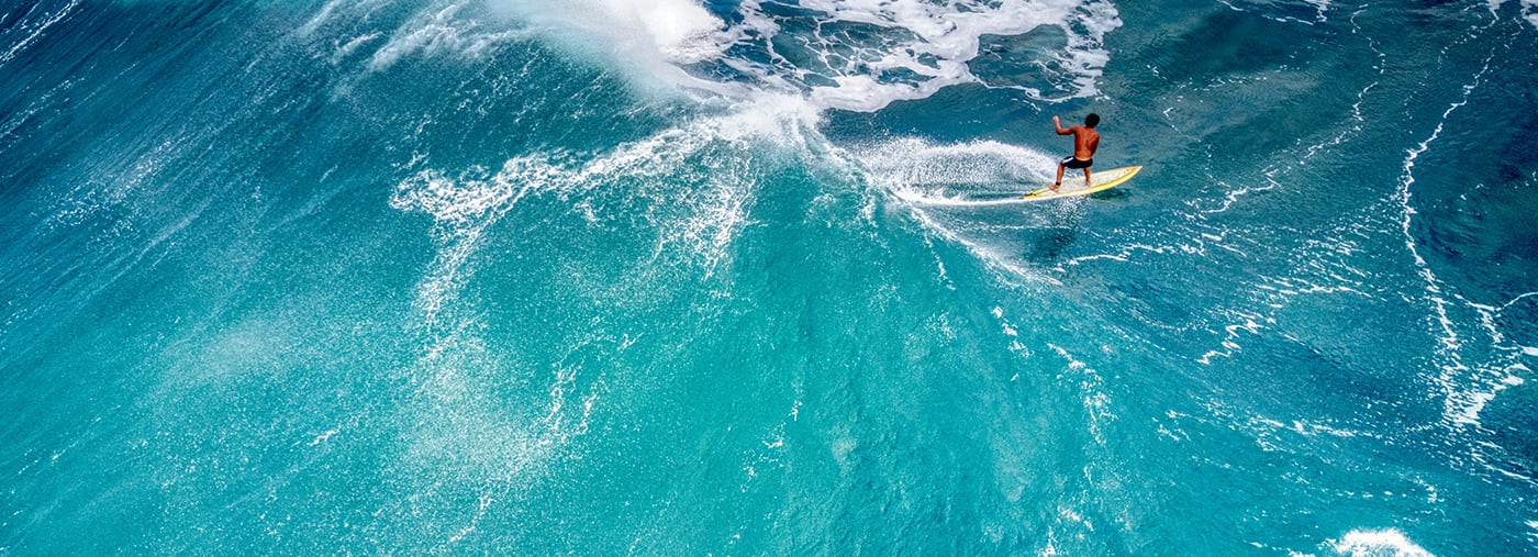 uma vista aérea traseira de um surfista que montava onda em hawaii praia do pôr sol trás situado na costa norte oahu
