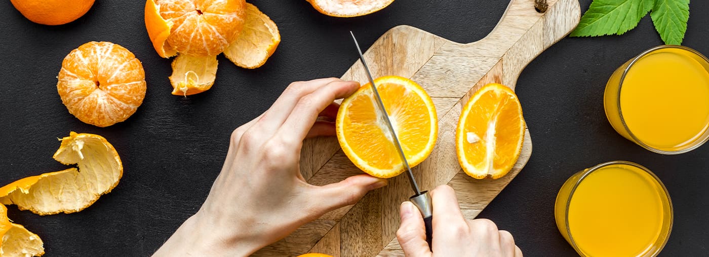 hands making orange juice on curring board