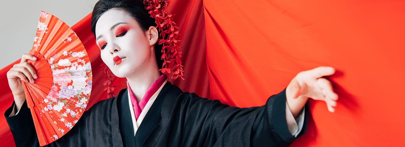 beautiful geisha in black kimono with hand fan and red cloth on background gesturing isolated on white panoramic shot geisha in