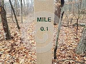 0.1 mile marker post in forest or woods with leaves