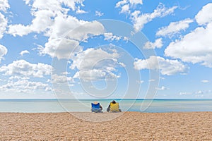 08-29-2020 West Bay, UK. A couple comfortably sitting in beach chairs enjoying undisturbed view at quiet and calm sea waters.