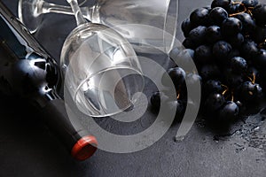 1 bottle of red wine, dark grapes, 2 glasses on a black background, top view