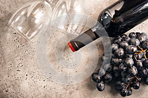 1 bottle of wine,  bunch of dark grapes, 2  empty glass, rose on a gray background  ,  copy space