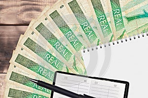 1 Brazilian real bills fan and notepad with contact book and black pen. Concept of financial planning and business strategy