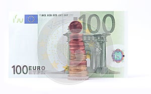 1 cent coin standing on top of stack of euro coins near 100 euro bank note.