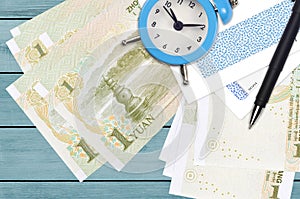 1 Chinese yuan bills and alarm clock with pen and envelopes. Tax season concept, payment deadline for credit or loan. Financial