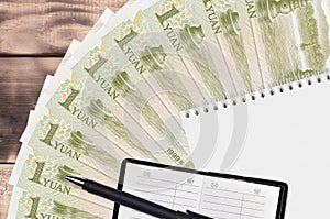 1 Chinese yuan bills fan and notepad with contact book and black pen. Concept of financial planning and business strategy