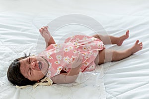 1-month-old baby newborn daughter, lying on a white bed and is crying