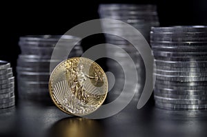 1 ounce gold coin infront of stacks of silver coins