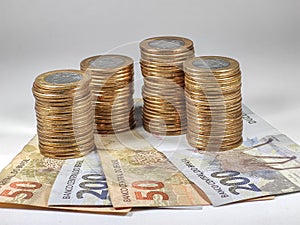 1 real coin stacks with 200 and 50 reais banknotes on white background. Concept of brazil economy, government investments.