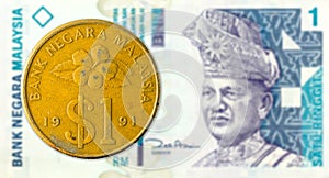 1 ringgit coin against 1 malaysian ringgit bank note obverse