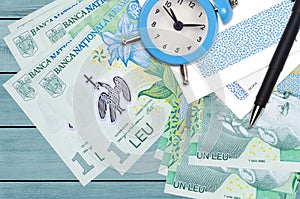 1 Romanian leu bills and alarm clock with pen and envelopes. Tax season concept, payment deadline for credit or loan. Financial