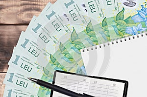 1 Romanian leu bills fan and notepad with contact book and black pen. Concept of financial planning and business strategy