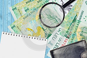 1 Romanian leu bills and magnifying glass with black purse and notepad. Concept of counterfeit money. Search for differences in