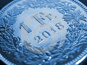 1 Swiss Franc coin close-up. Blue background or wallpaper about economy, business or banking. Money and Central Bank in