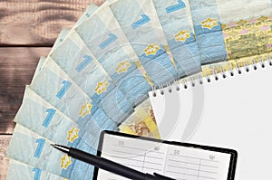 1 Ukrainian hryvnia bills fan and notepad with contact book and black pen. Concept of financial planning and business strategy