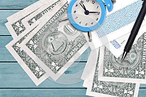 1 US dollar bills and alarm clock with pen and envelopes. Tax season concept, payment deadline for credit or loan. Financial