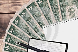 1 US dollar bills fan and notepad with contact book and black pen. Concept of financial planning and business strategy