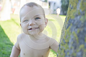 1 year baby boy playing hide-and-seek on swimming pool grass