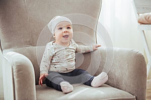 1 year girl wearing stylish clothes, sitting in a vintage chair in the room.