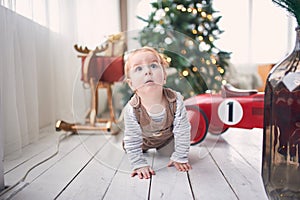 1 year old baby boy crawling on floor at home. christmas decorations on a background