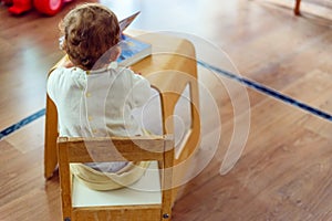 1 year old baby sitting on his back in a chair to read a book