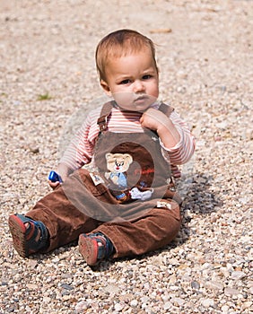 1 year old baby sitting on pebble