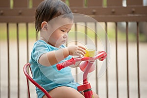 1 year old Chinese Asian boy wearing rompers riding a bicycle