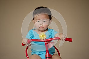 1 year old Chinese Asian boy wearing rompers riding a bicycle
