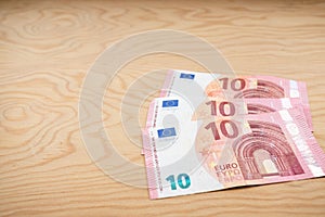 10 Euros notes fanned out on a light wood background