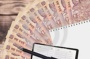 10 Indian rupees bills fan and notepad with contact book and black pen. Concept of financial planning and business strategy
