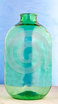A 10 liter glass jar is made of thick green glass on a blue background