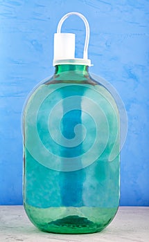 A 10 liter glass jar is made of thick green glass with a nylon cover with a water lock on a blue background