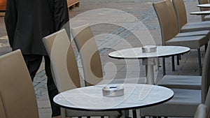 10 October 2021 - Strasbourg, France: Deserted empty cafe tables by which passers-by pass