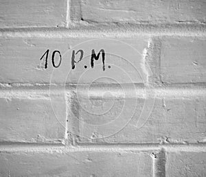 10 P.M. WRITTEN ON WHITE PLAIN BRICK WALL