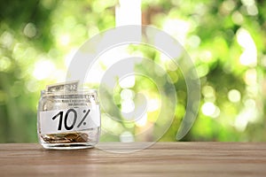 10 PERCENT written on paper and money in jar against blurred background