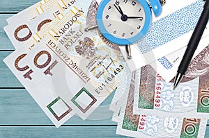 10 Polish zloty bills and alarm clock with pen and envelopes. Tax season concept, payment deadline for credit or loan. Financial
