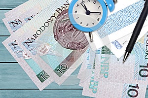10 Polish zloty bills and alarm clock with pen and envelopes. Tax season concept, payment deadline for credit or loan. Financial