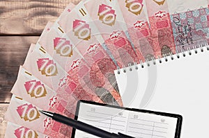 10 Ukrainian hryvnias bills fan and notepad with contact book and black pen. Concept of financial planning and business strategy