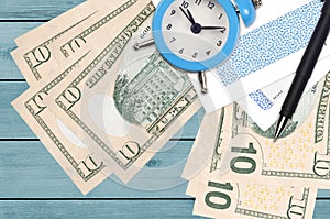 10 US dollars bills and alarm clock with pen and envelopes. Tax season concept, payment deadline for credit or loan. Financial
