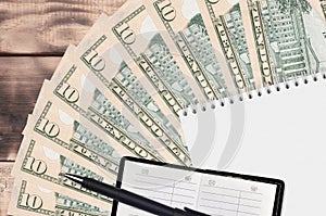 10 US dollars bills fan and notepad with contact book and black pen. Concept of financial planning and business strategy