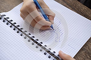 10-year-old boy drawing graphic dictation in checkered notebook, moving one line to left and two cells down, Development of