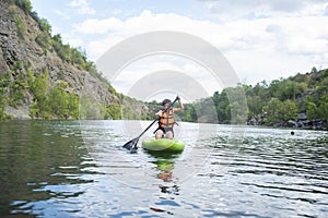 A 10-year-old boy rides a SUP board alone on a mountain lake, river, canyon.