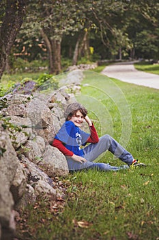 10 year old boy sitting in front of a stone wall