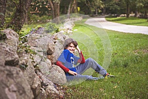 10 year old boy sitting in front of a stone wall
