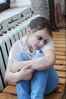 10-year-old girl sitting near   window and   sad