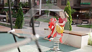 A 10-year-old girl swings on a children's attraction in the form of a deer on the playground.