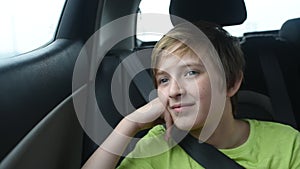 A 10 year old smiling boy sits in the passenger seat in a car.