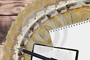 100 Canadian dollars bills fan and notepad with contact book and black pen. Concept of financial planning and business strategy